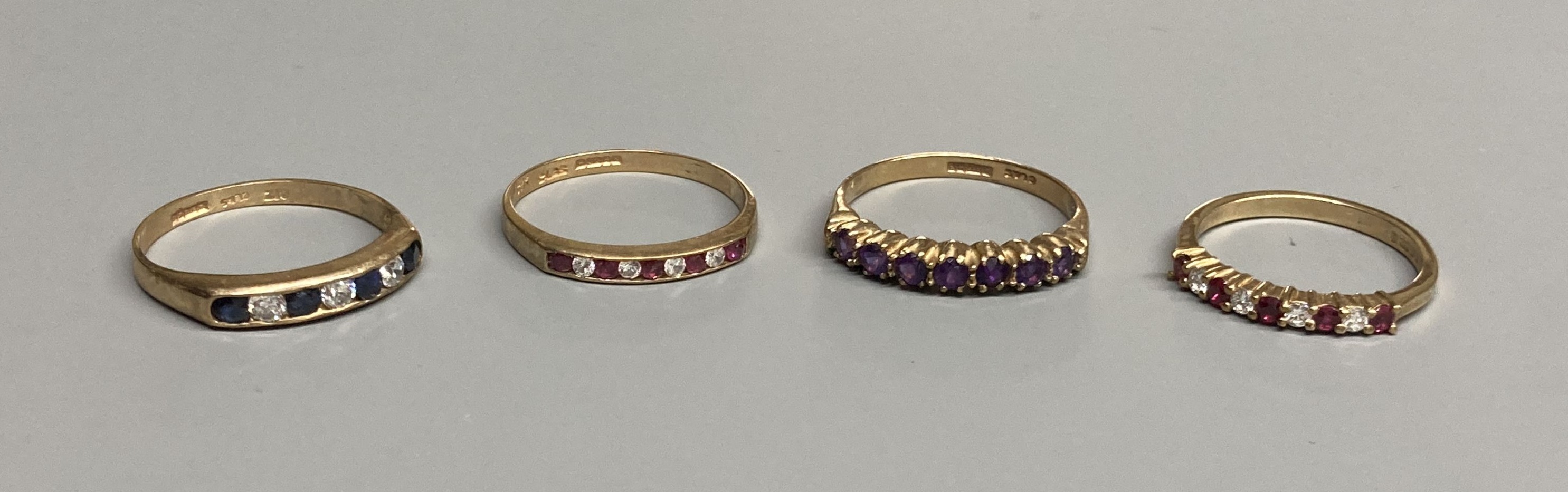 A modern 9ct gold, ruby and diamond set half hoop ring and a similar amethyst ring and two other 9ct gold gem set rings